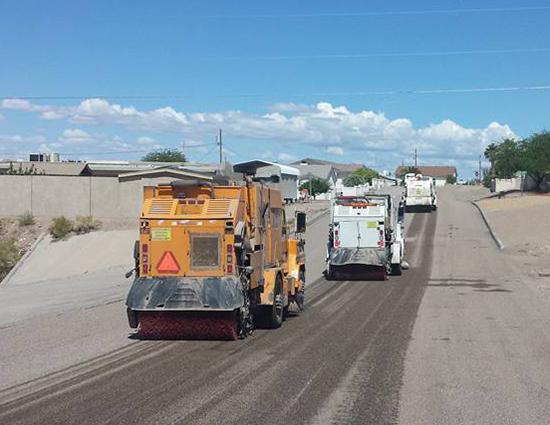 Three Swept Away Street Cleaners sweeping sand off street.