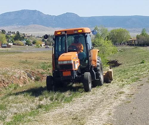 Swept Away AZ tractor mowing grass in field.