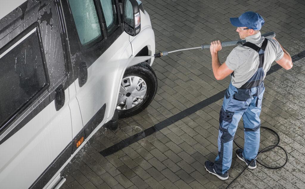 Swept Away employee pressure washing a vehicle.